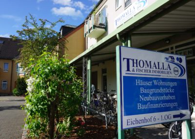Hinweisschild von Thomalla & Fischer Immobilien am Eingang: Häuser, Wohnungen, Baugrundstücke, Baufinanzierungen, Eichenhof 6, 1. OG