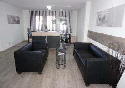 Wartebereich im Büro von Thomalla & Fischer Immobilien mit Ledersofas und Blick zum Empfang
