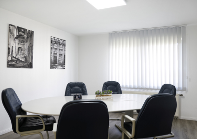 Besprechungsraum im Büro von Thomalla & Fischer Immobilien mit runder Tischgruppe und schwarzen Lederstühlen