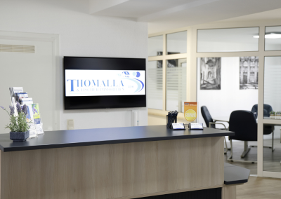 Empfangstresen im Büro von Thomalla & Fischer Immobilien mit Bildschirm, auf dem das Firmenlogo zu sehen ist