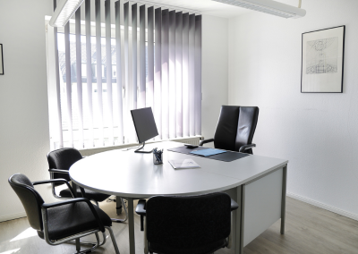 Beratungsplatz im Büro von Thomalla & Fischer Immobilien mit rundem Tisch, Laptop und Lederstühlen vor dem Fenster