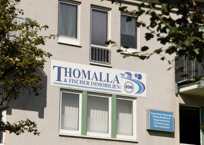Hausfassade mit dem Firmenschild von Thomalla & Fischer Immobilien über dem Eingang