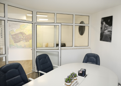 Besprechungsraum im Büro von Thomalla & Fischer Immobilien mit weißem Tisch, schwarzen Stühlen und Karte an der Wand